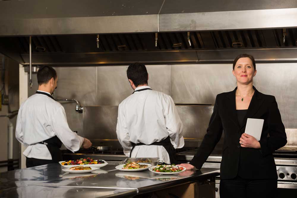 catering event planner in kitchen with chefs